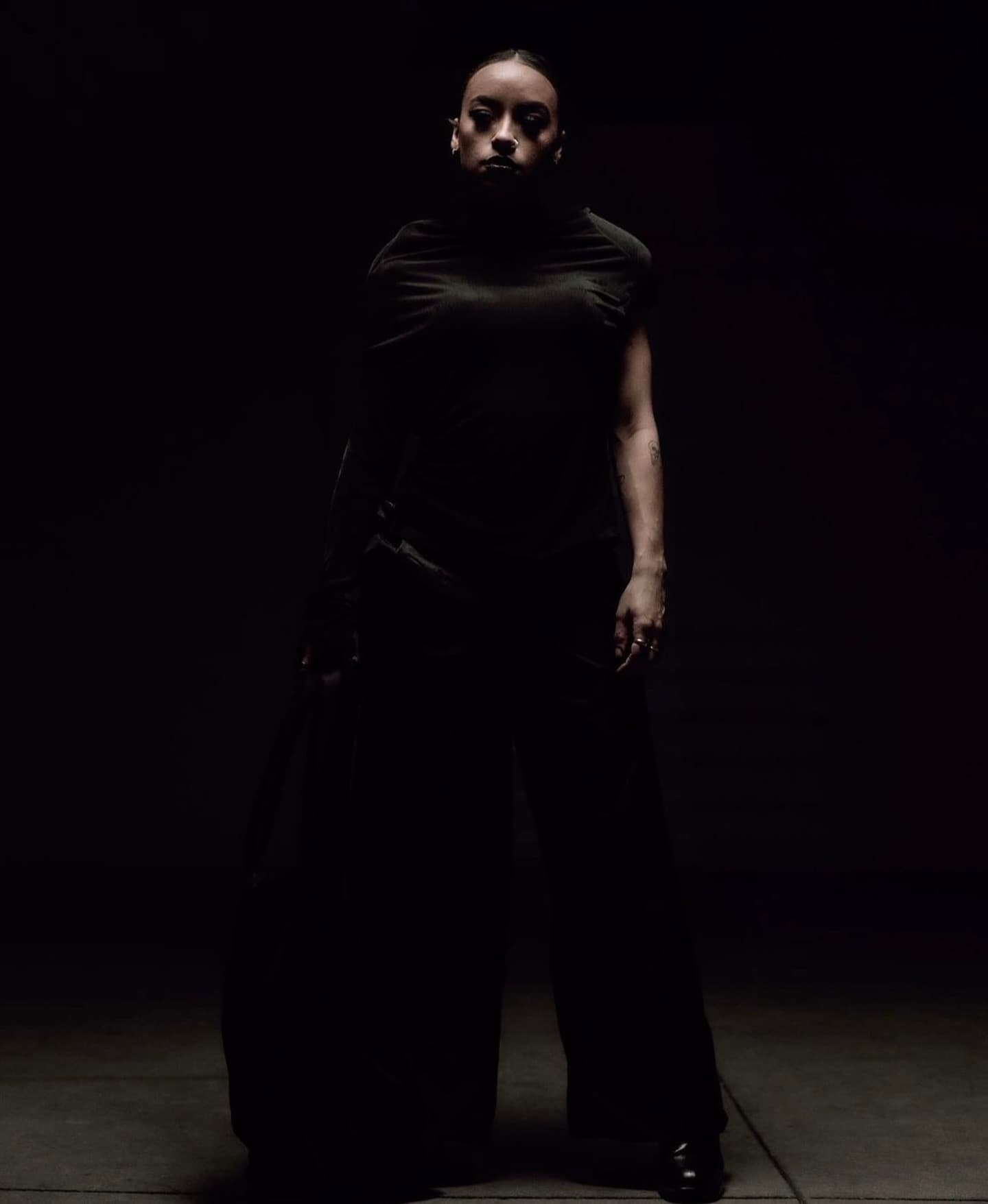 Wide-leg tailoring and sculpted matte complexion against the dark