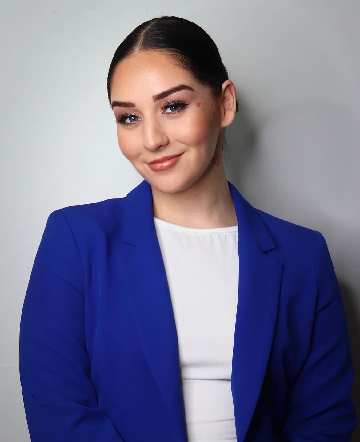 Polished portrait in a cobalt blazer with soft rose glam and a sleek bun